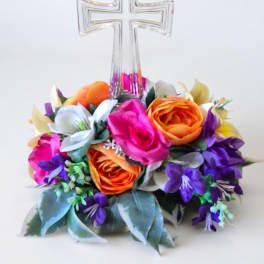 Floral arrangement with a clear cross topper and bright mixed blooms