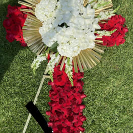 Tall red and white standing easel arrangement with gold fan accents on grass