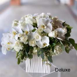 White orchids and roses arranged in a ribbed white vase