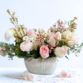 Pastel bouquet of roses and ranunculus in a textured vase