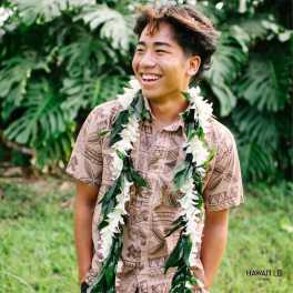 Person wearing a white flower lei over a patterned shirt