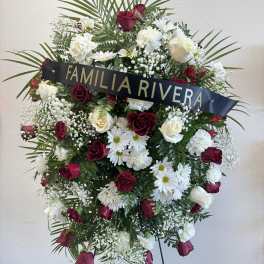 Standing funeral wreath of red and white flowers with a name ribbon