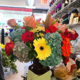 Mixed bouquet of roses, gerbera daisies, and hydrangeas in a vase