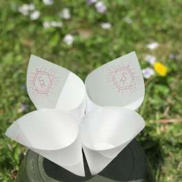 Four white paper cone holders with pink monogram marks on a dark base