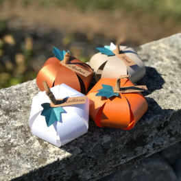 Four paper pumpkins with name tags arranged on a stone surface