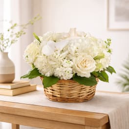 White floral arrangement in a wicker basket on a table