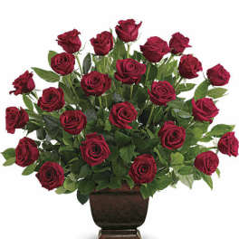 Red roses arranged in a dark pedestal vase