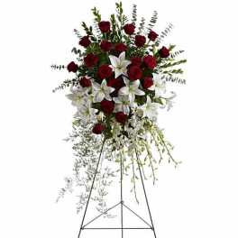 Standing floral spray with red roses and white lilies on an easel