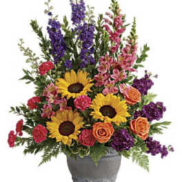 Colorful mixed flower arrangement in a gray vase with sunflowers and roses