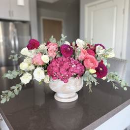 Pink and white floral arrangement in a white pedestal vase