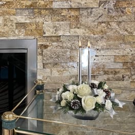 White rose arrangement with candles in a low silver container