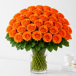 Orange roses arranged in a clear glass vase.