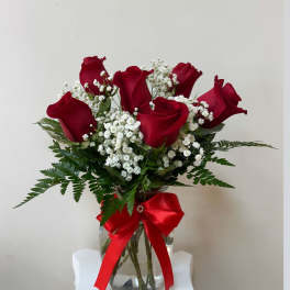 Red roses in a glass vase with baby's breath and a red ribbon