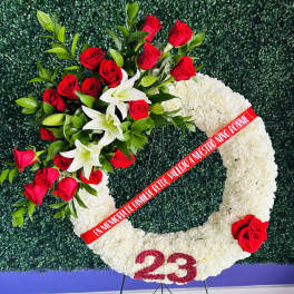 White floral funeral wreath with red roses and lilies on a stand