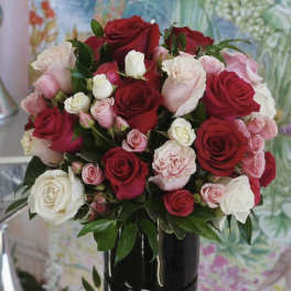 Bouquet of red, pink, and white roses in a black vase