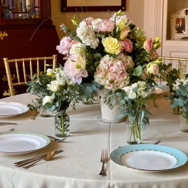 Pastel floral centerpiece with roses and hydrangeas on a dining table