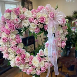 Heart-shaped arrangement of pink and white roses with a sheer ribbon