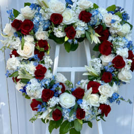 Heart-shaped floral wreath with red and white roses and blue flowers