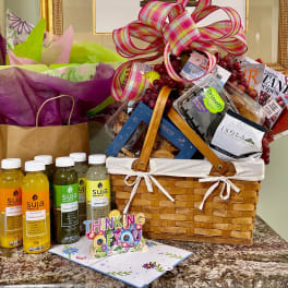 Gift basket with snacks, juice bottles, and a large plaid ribbon bow