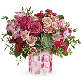 Pink and blush roses arranged in a patterned glass vase