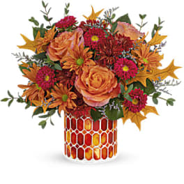 Autumn bouquet of orange roses and pink mums in a patterned vase