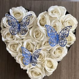 Heart-shaped arrangement of white roses with blue butterfly decorations