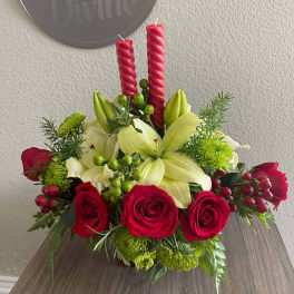 Red roses and pale lilies arranged with candles in a low centerpiece