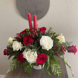 Red and white rose arrangement with two red candles in a white container