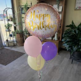 Birthday balloon bouquet with a large round foil balloon and pastel latex balloons