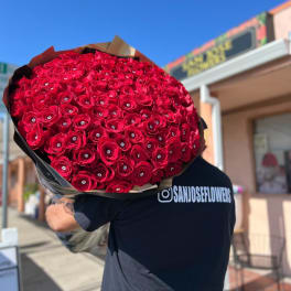 Large bouquet of red roses with jeweled centers wrapped in dark paper