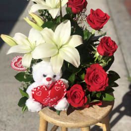 Bouquet of red roses and white lilies with a teddy bear holding a heart