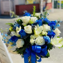 Blue and white rose bouquet in a glass vase with a ribbon
