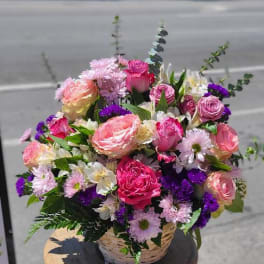 Basket of pink and purple mixed flowers on a stool