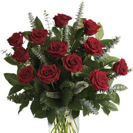 Red roses arranged in a clear glass vase with eucalyptus