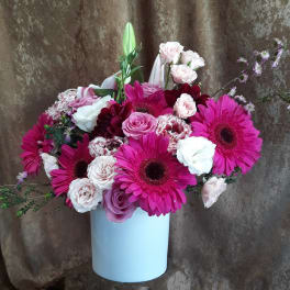 Pink gerbera daisies and roses arranged in a white vase