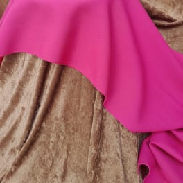 Bright pink fabric draped over a brown textured surface