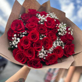 Bouquet of red roses with white baby's breath in brown paper