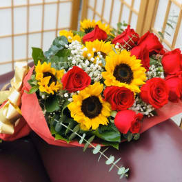 Bouquet of red roses and yellow sunflowers wrapped in pink paper