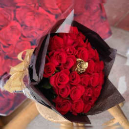 Bouquet of red roses wrapped in black paper with a gold ribbon