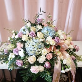 Large pastel floral arrangement with roses, hydrangeas, and carnations on a table