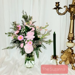 Pink floral arrangement in a clear glass vase beside a green candle holder
