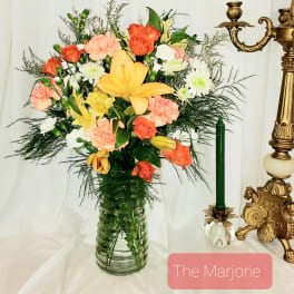 Mixed bouquet of orange, yellow, pink, and white flowers in a glass vase