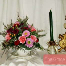 Mixed bouquet in a white bowl with a green candle beside it