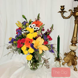 Colorful mixed bouquet in a clear glass vase with lilies and roses