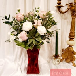 Pink and white roses in a red glass vase