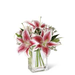 Pink and white lilies arranged in a clear glass vase