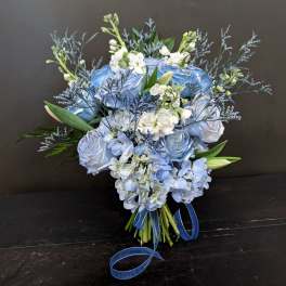 Blue and white bouquet with roses, hydrangeas, and lilies tied with ribbon