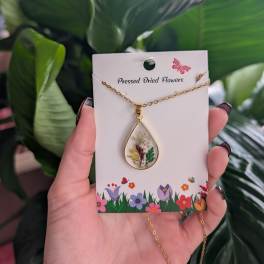 Gold teardrop necklace with pressed dried flowers on a display card