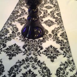 Black glass vase on a black-and-white patterned table runner