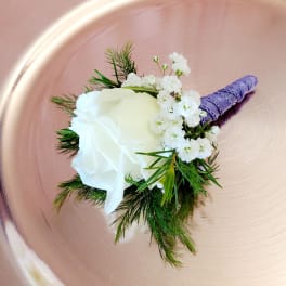 White rose boutonniere with baby's breath and purple wrapped stem